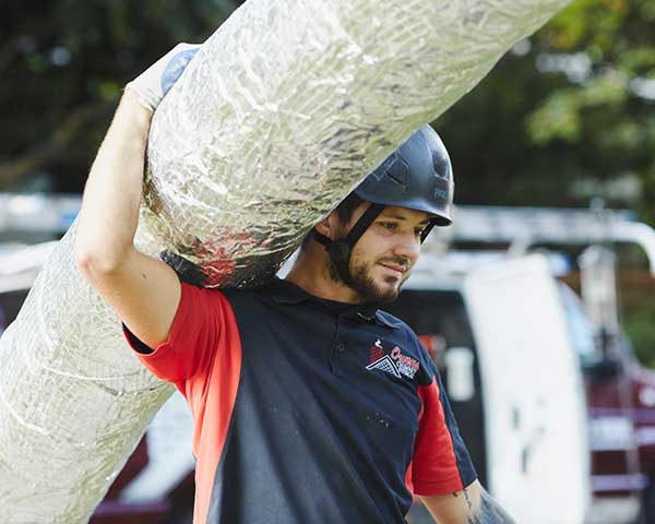 Chimney technician carrying a stainless steel chimney liner on his shoulder