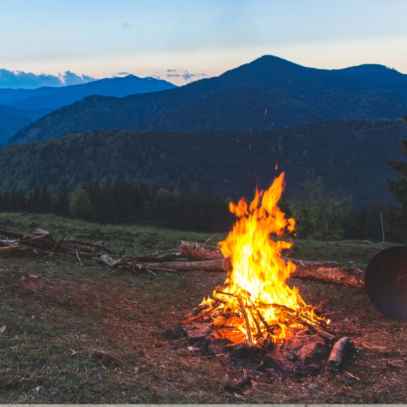 an outdoor fire with mountains in the background