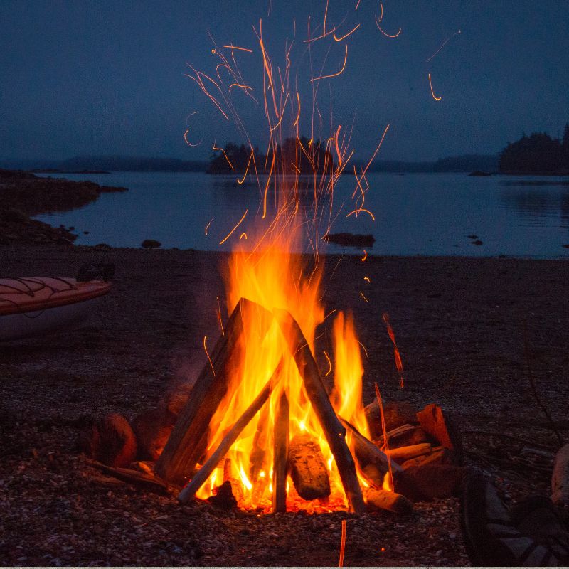 an outdoor fire with a lake in the background